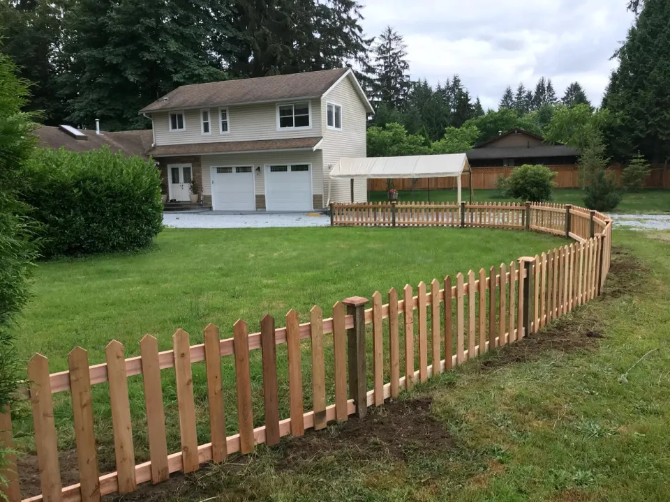 Curved cedar picket fence around a front lawn