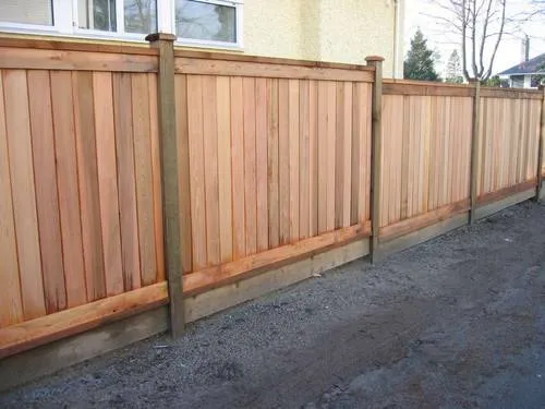 Cedar privacy fence with framed panels along a gravel lane