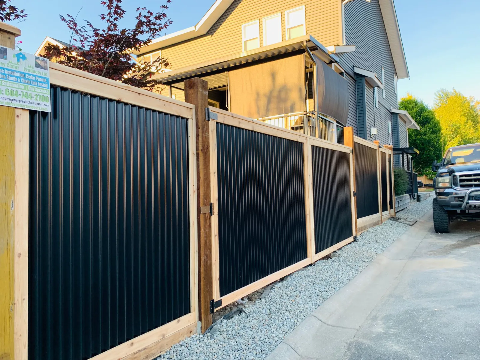 Cedar-framed black steel fence with matching gates beside a driveway