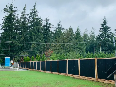Long cedar-framed steel fence around a large open field