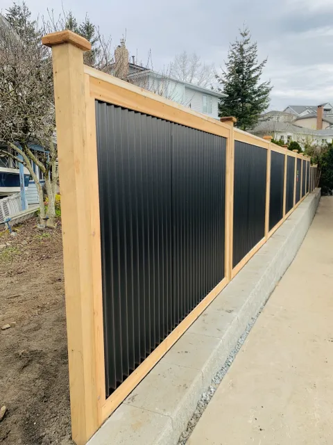 Tall cedar posts with black corrugated steel panels along a sidewalk