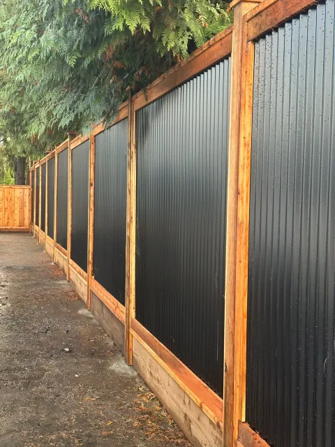 Cedar-framed black steel fence on a concrete curb along a walkway