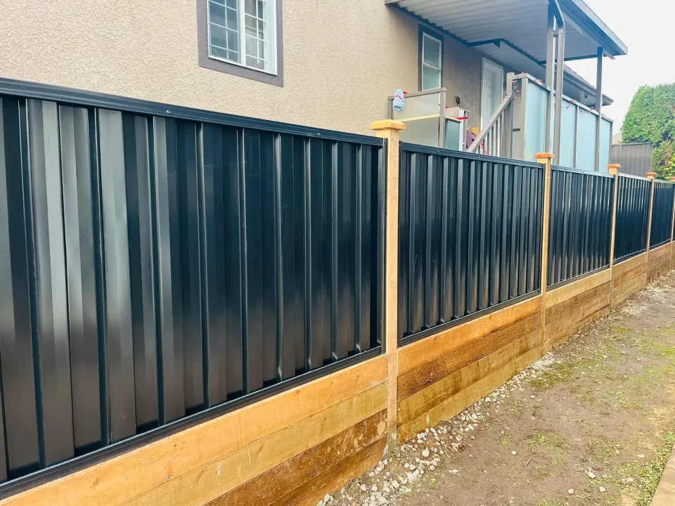 Black steel fence panels on top of a cedar timber retaining wall