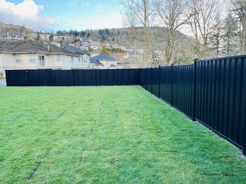 Black steel privacy fence around a new lawn with mountains behind