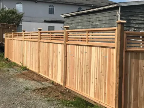 Cedar fence with a horizontal slat top along a house