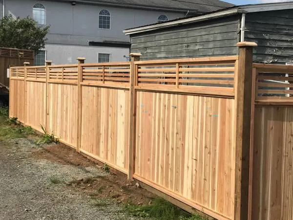 Cedar fence with a horizontal slat top along a house