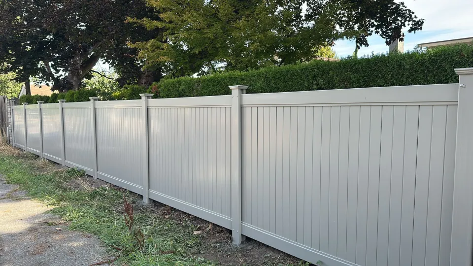 Long run of grey vinyl privacy fence along a lane