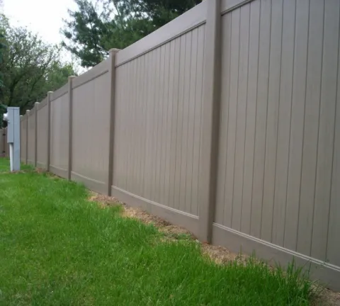 Tan vinyl privacy fence beside a lawn